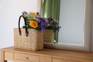 Photo of Wicker basket with beautiful flowers on wooden table indoors, space for text