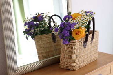 Photo of Wicker basket with beautiful flowers on wooden table indoors