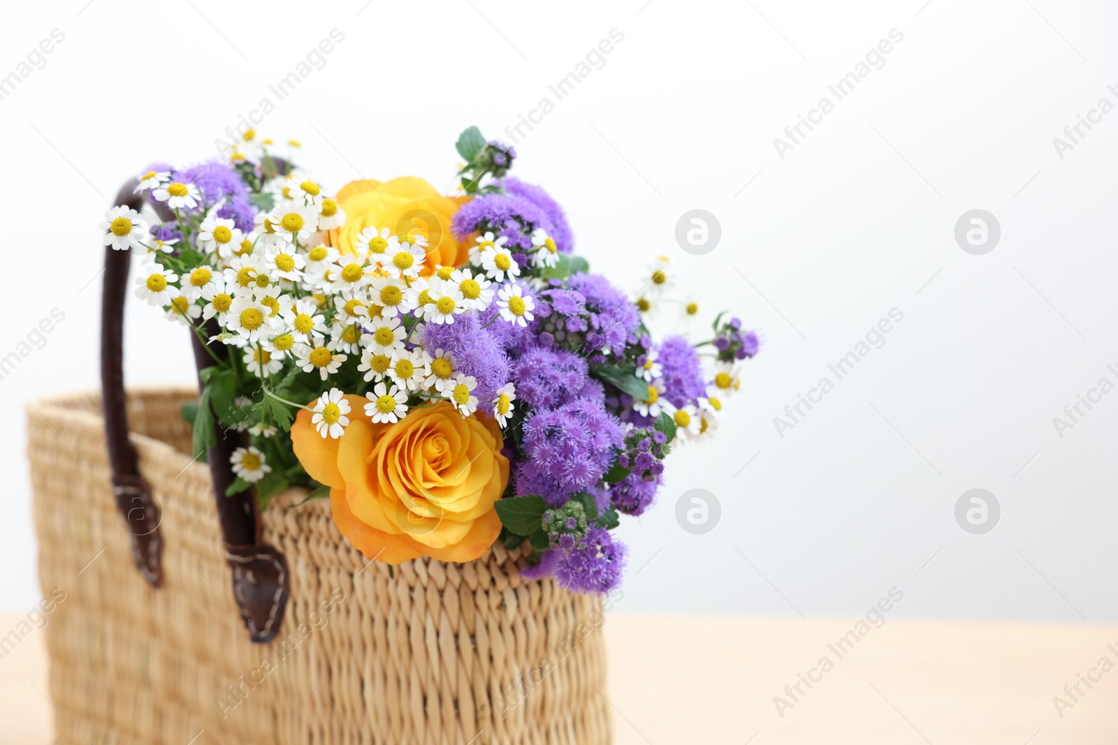 Photo of Wicker basket with beautiful flowers on table, closeup. Space for text