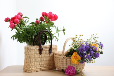 Wicker baskets with beautiful flowers on light wooden table