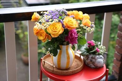 Photo of Vase with beautiful flowers on red table at balcony