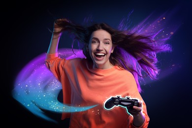 Excited woman playing video game with controller on dark background. Colorful light coming out from device