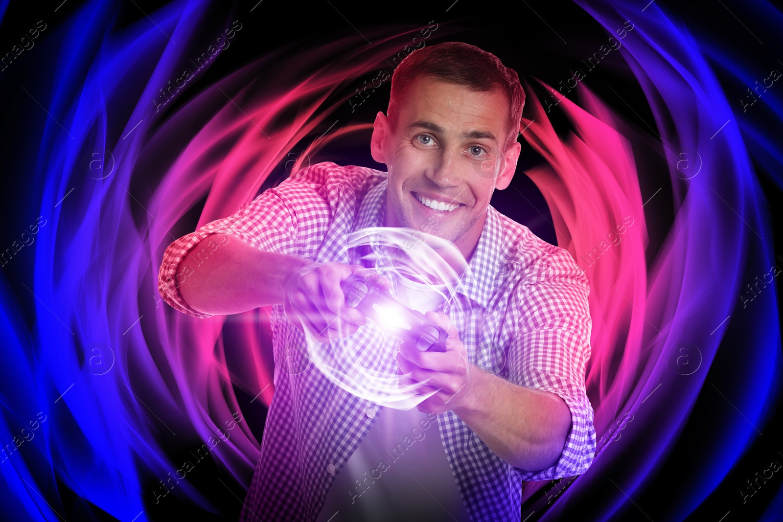 Image of Happy man playing video game with controller on bright background. Light coming out from device