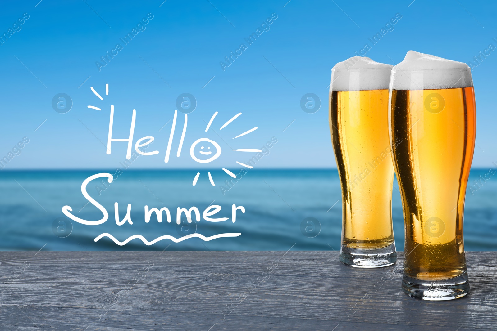 Image of Hello Summer. Glasses of beer on wooden table near ocean