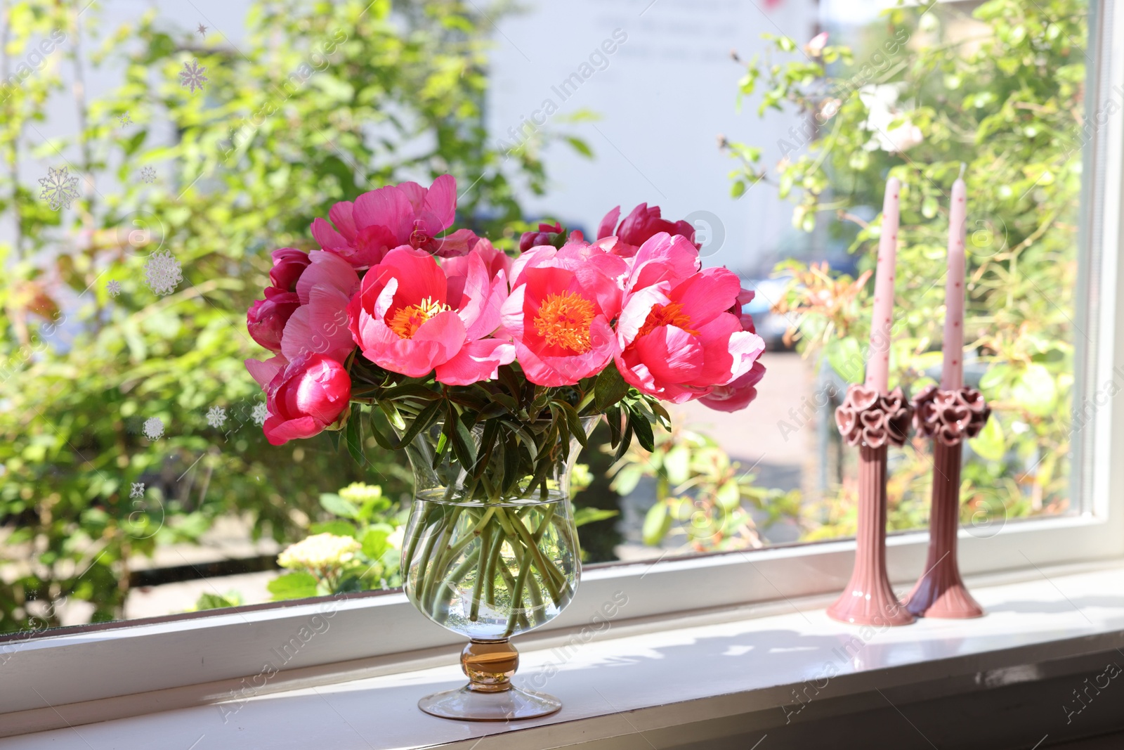 Photo of Beautiful pink peonies in vase and candles on windowsill