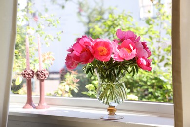 Photo of Beautiful pink peonies in vase and candles on windowsill