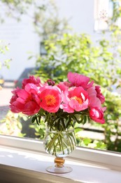 Beautiful pink peonies in vase on windowsill