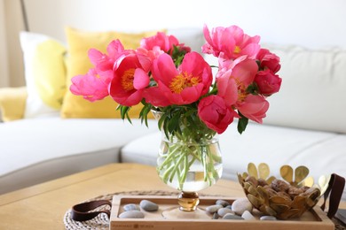Photo of Beautiful pink peonies in vase and decorative stones on wooden table indoors