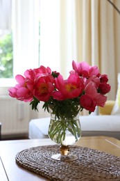 Photo of Beautiful pink peonies in vase on wooden table indoors