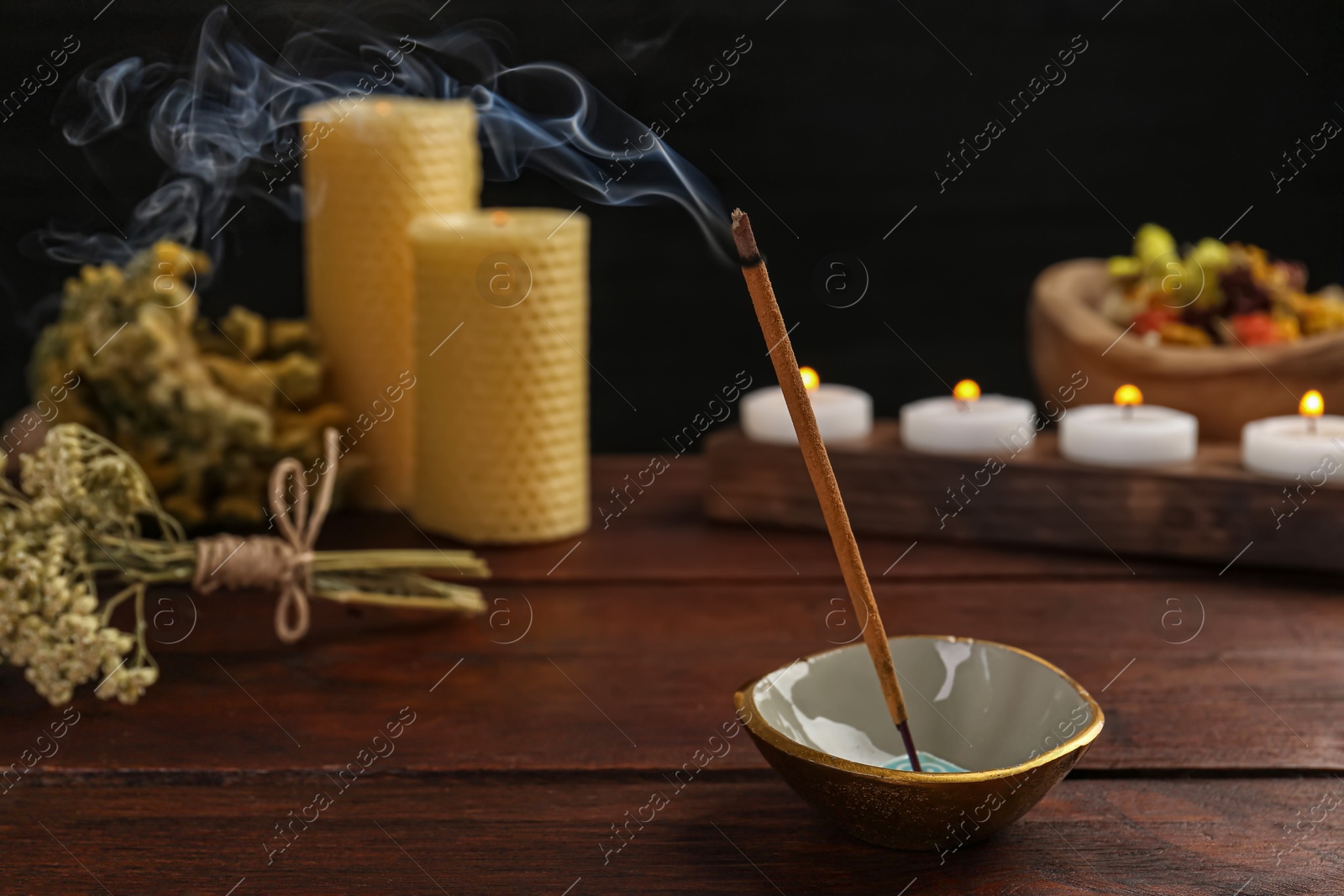 Photo of Aromatic incense stick smoldering on wooden table