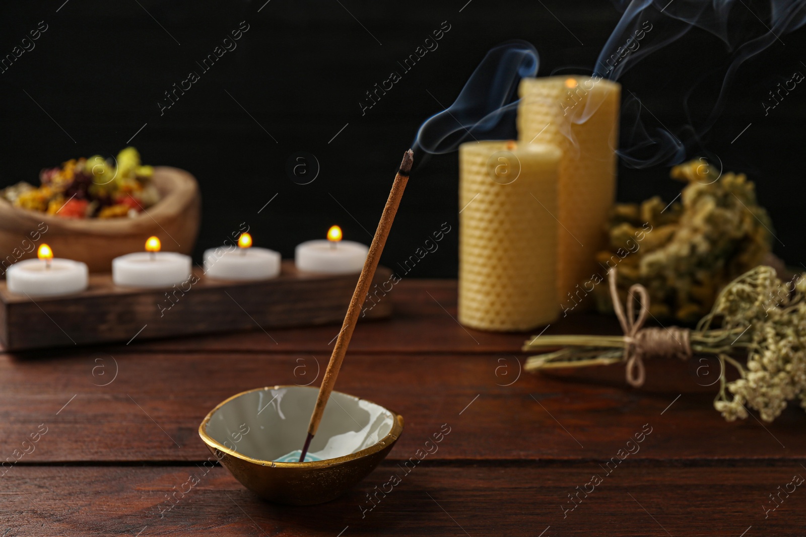 Photo of Aromatic incense stick smoldering on wooden table