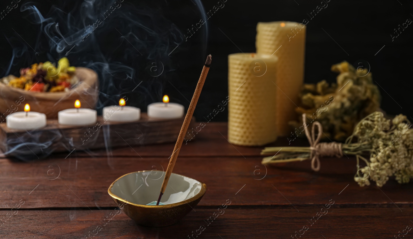 Photo of Aromatic incense stick smoldering on wooden table