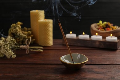 Photo of Aromatic incense stick smoldering on wooden table