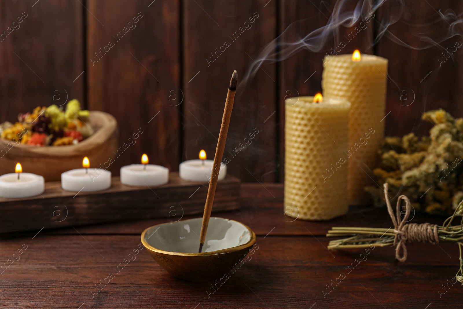 Photo of Aromatic incense stick smoldering on wooden table