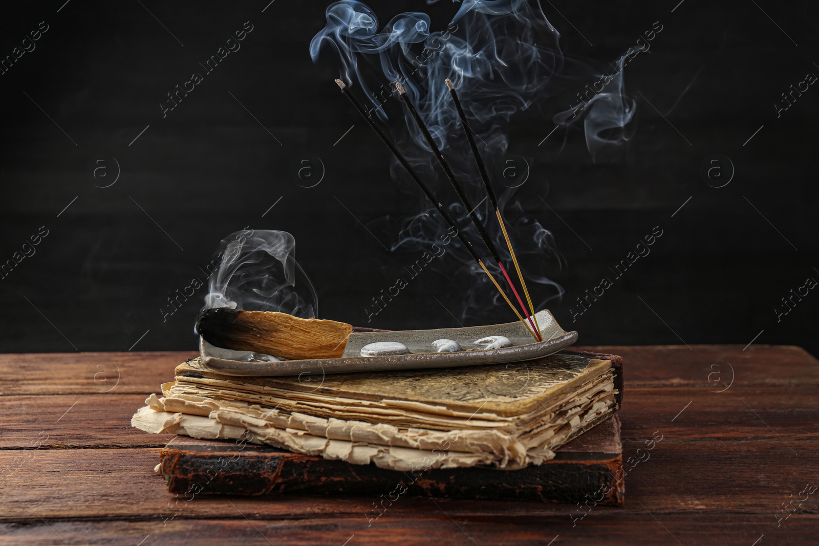 Photo of Aromatic incense sticks smoldering on wooden table