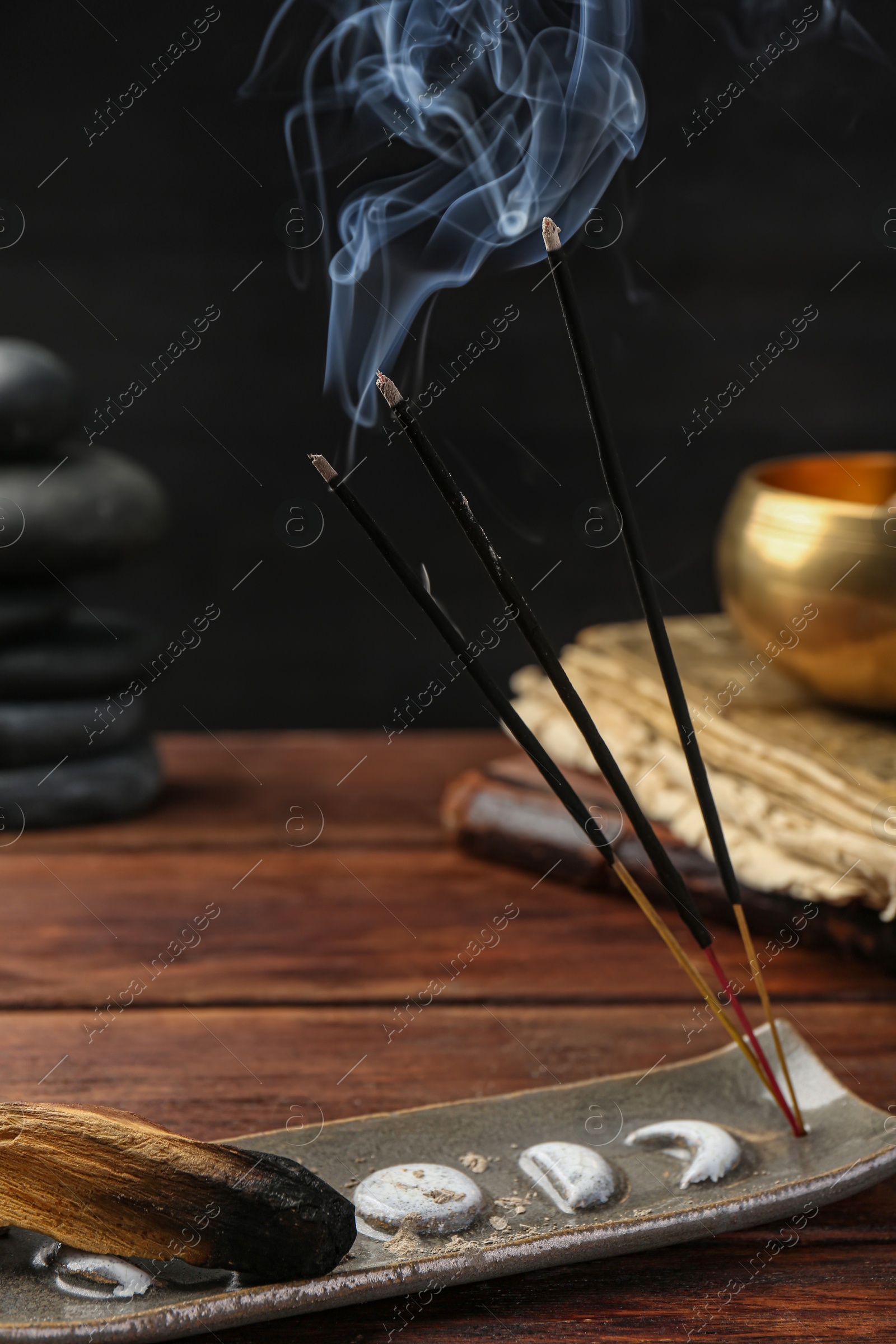 Photo of Aromatic incense sticks smoldering on wooden table