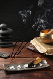 Photo of Aromatic incense sticks smoldering on wooden table