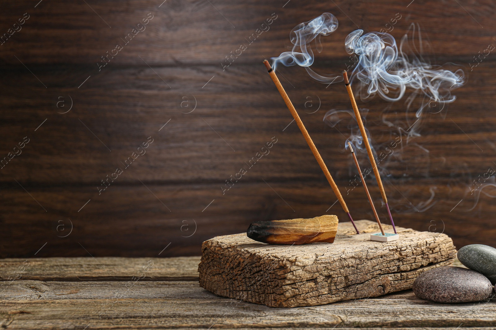 Photo of Aromatic incense sticks smoldering on wooden table. Space for text