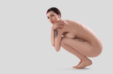 Beautiful nude woman with tattoos posing on white background