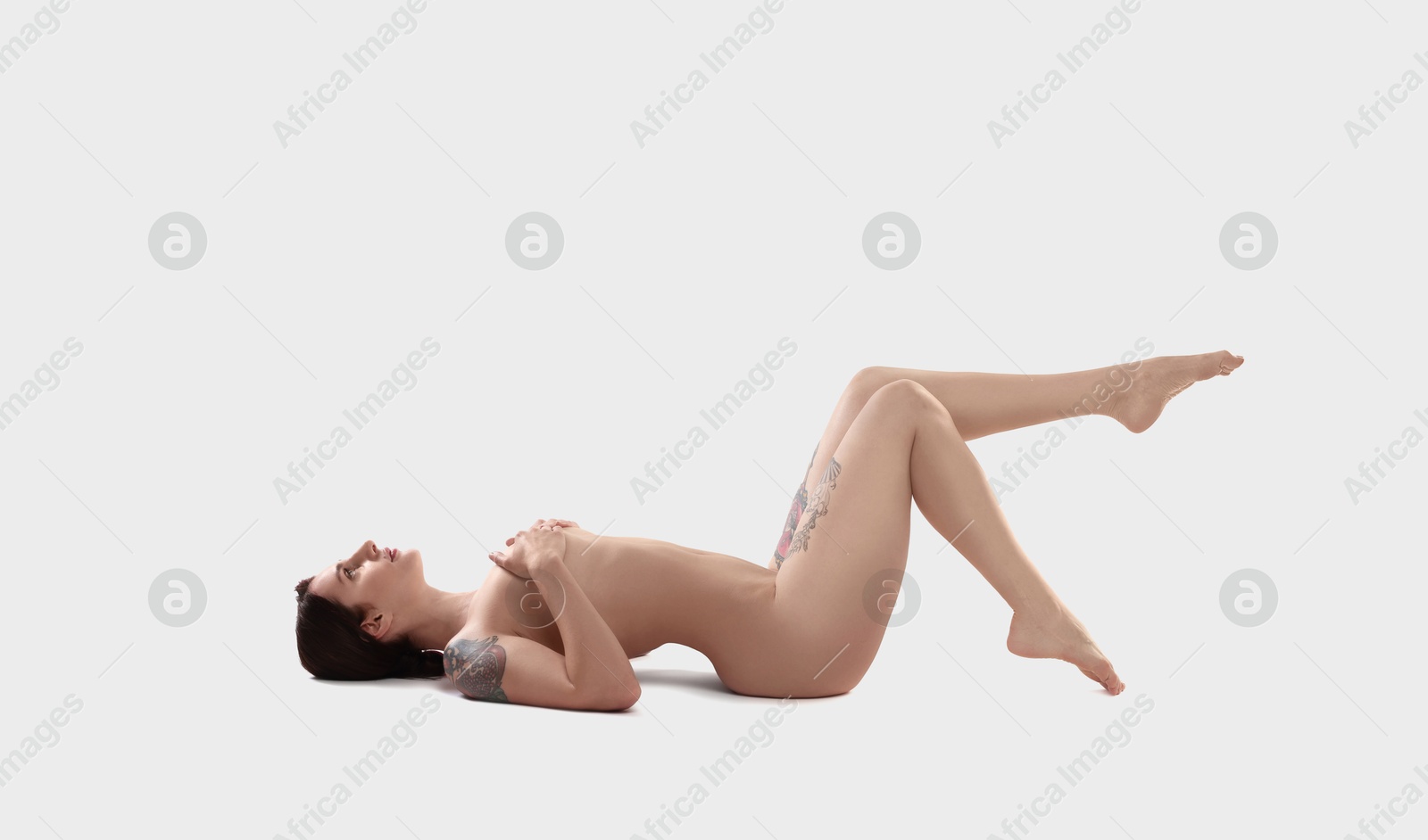 Photo of Beautiful nude woman with tattoos posing on white background