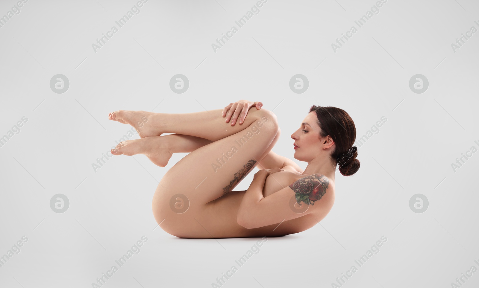 Photo of Beautiful nude woman with tattoos posing on white background