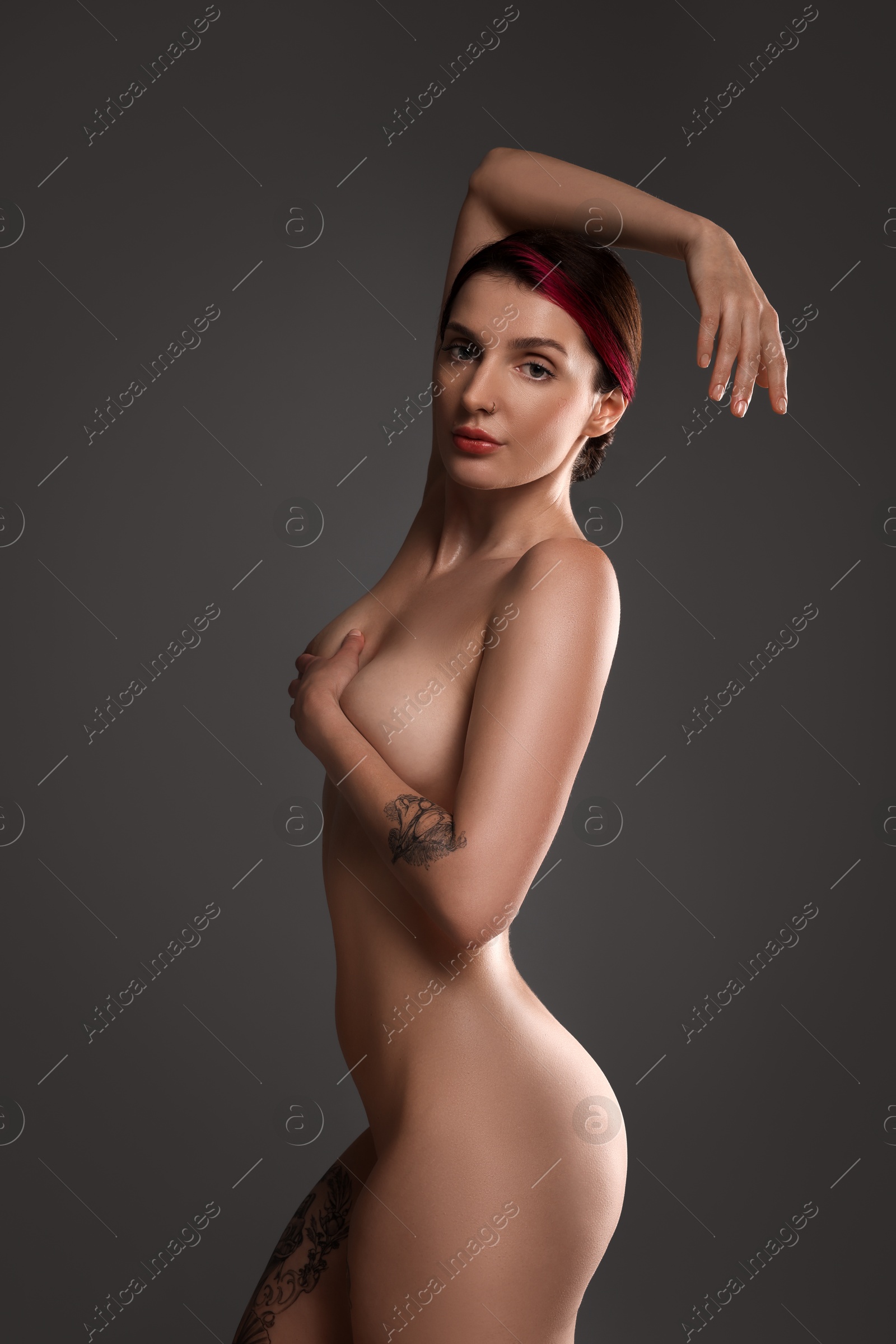 Photo of Beautiful nude woman with tattoos posing on dark background