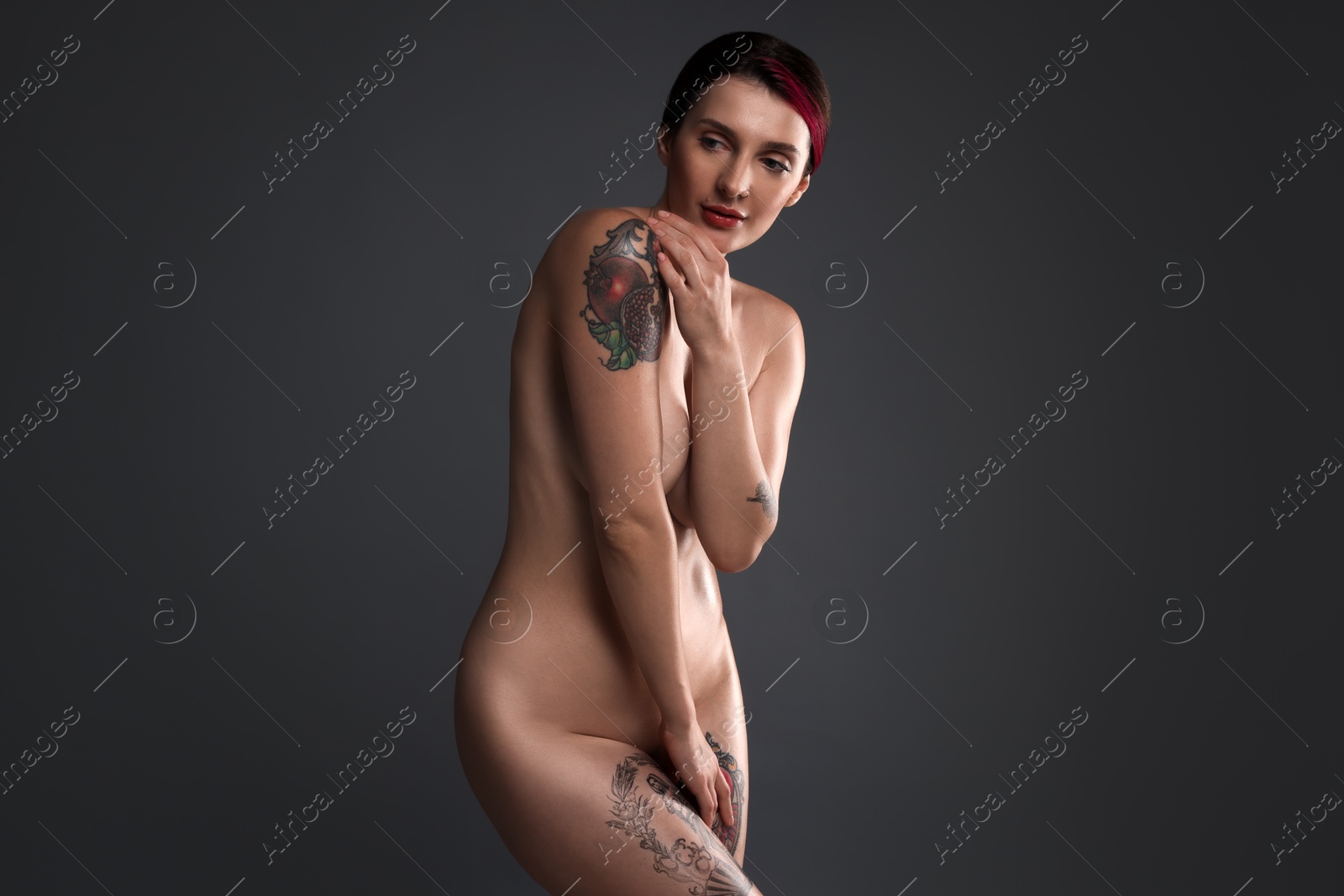 Photo of Beautiful nude woman with tattoo posing on dark background