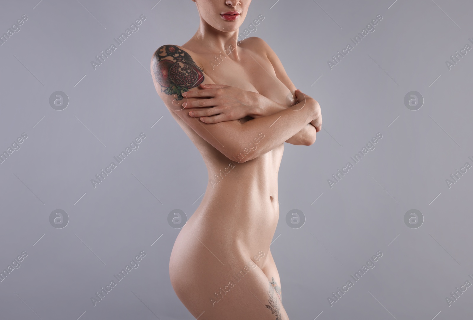 Photo of Nude woman with tattoo on light grey background, closeup