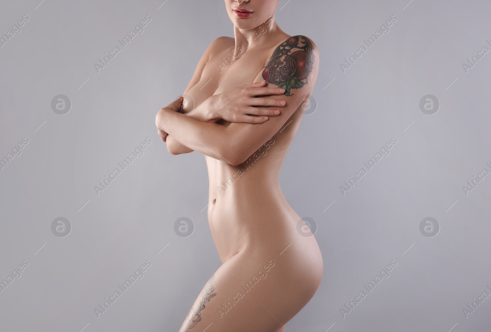 Photo of Nude woman with tattoo on light grey background, closeup. Space for text