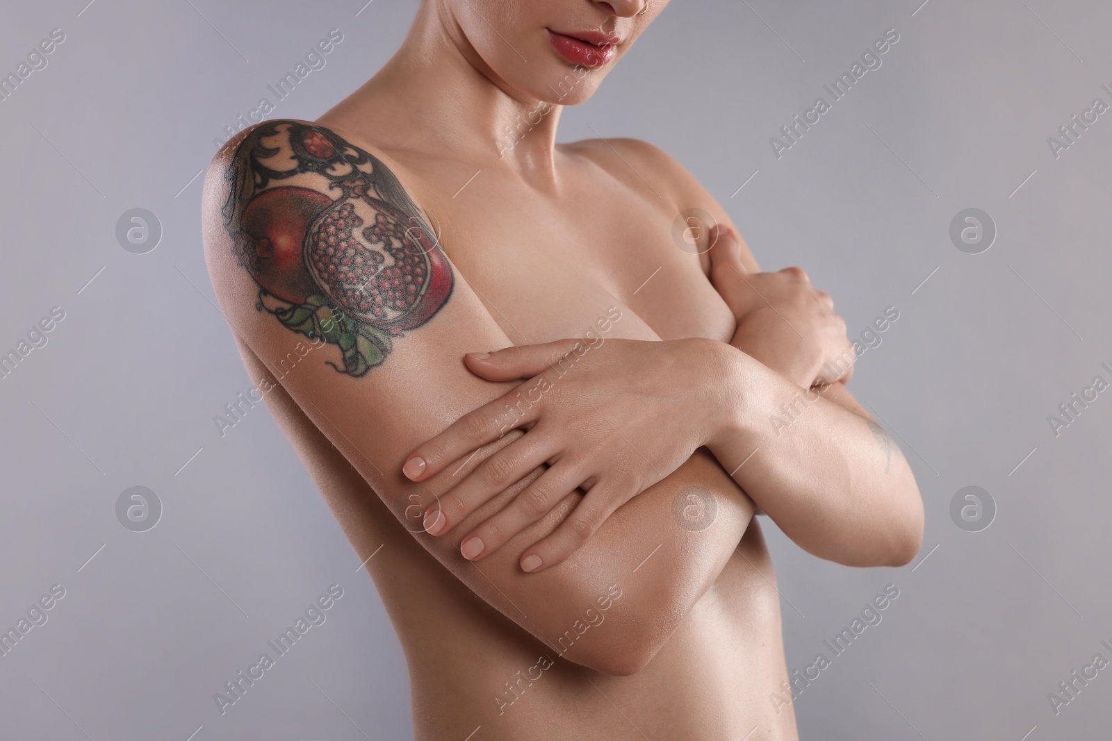 Photo of Nude woman with tattoo on light grey background, closeup