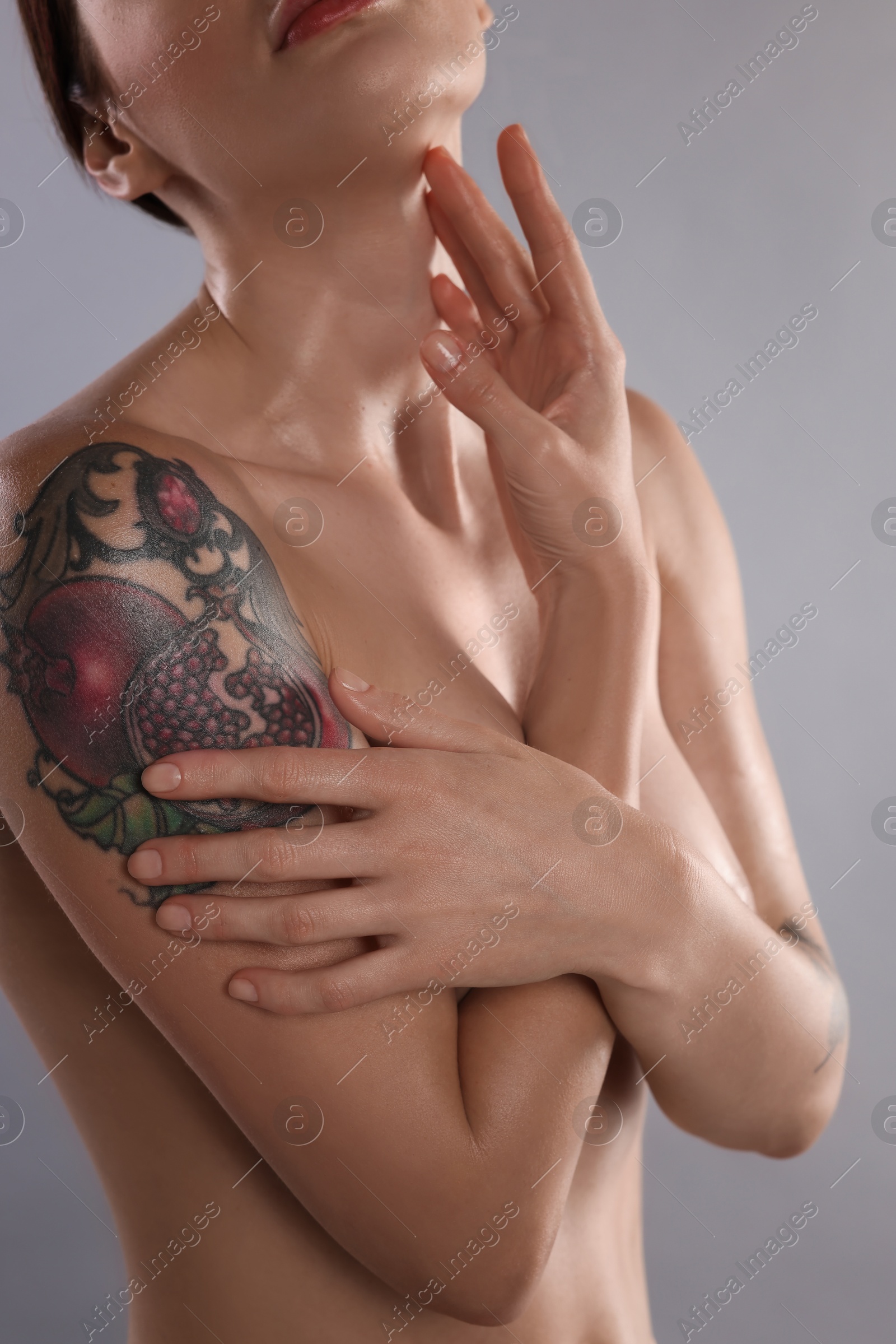 Photo of Nude woman with tattoo on light grey background, closeup