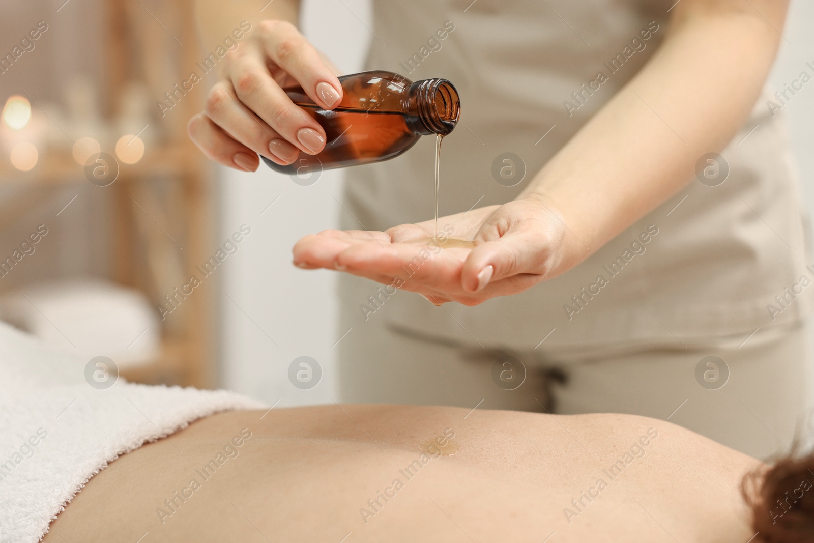 Photo of Aromatherapy. Woman receiving back massage with oil in spa salon, closeup