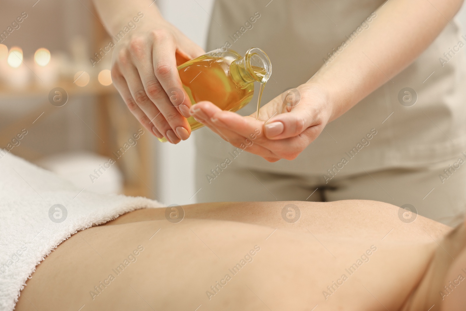 Photo of Aromatherapy. Woman receiving back massage with oil in spa salon, closeup