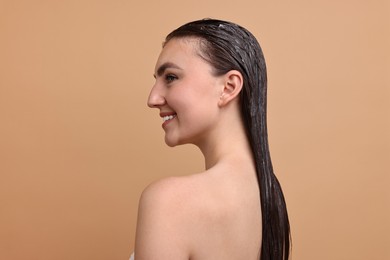 Photo of Smiling woman with applied hair mask on beige background