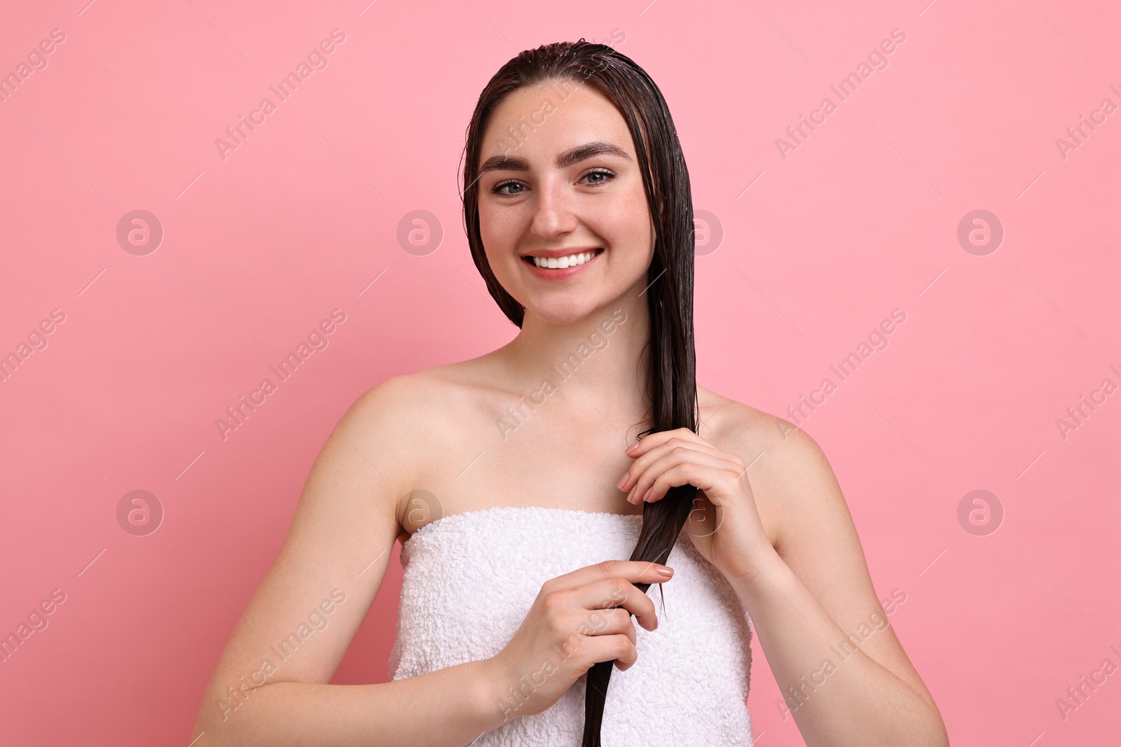 Photo of Smiling woman applying hair mask on pink background