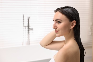 Beautiful woman with applied hair mask in bathroom. Space for text