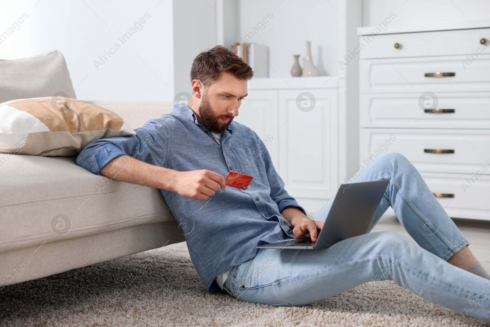 Photo of Online banking. Young man with credit card and laptop paying purchase at home