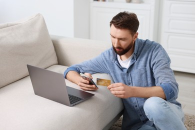 Online banking. Young man with credit card and laptop paying purchase at home