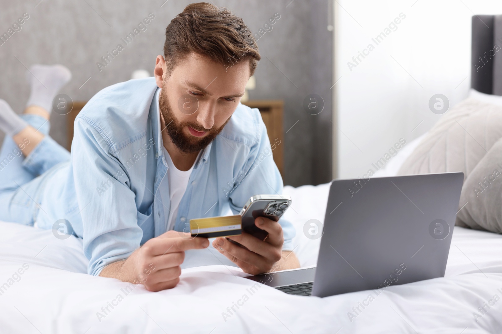 Photo of Online banking. Young man with credit card and laptop paying purchase at home
