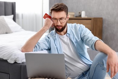 Photo of Online banking. Young man with credit card and laptop paying purchase at home