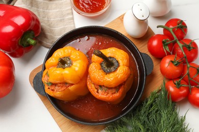 Photo of Tasty stuffed peppers in pan and products on light table, flat lay