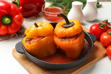 Photo of Tasty stuffed peppers in pan on light table, closeup