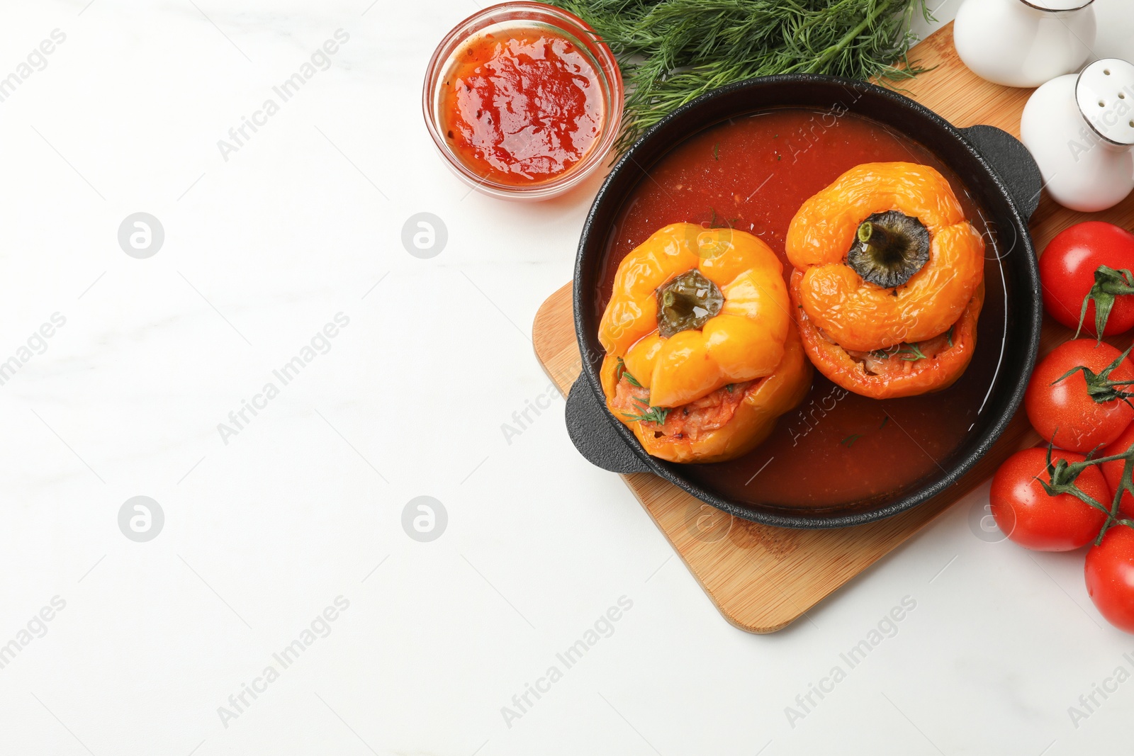 Photo of Tasty stuffed peppers in pan and products on light table, closeup. Space for text