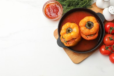 Photo of Tasty stuffed peppers in pan and products on light table, closeup. Space for text