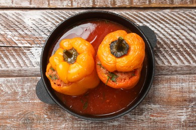 Photo of Tasty stuffed peppers in pan on wooden rustic table, top view