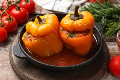 Photo of Tasty stuffed peppers in pan and products on wooden rustic table, closeup