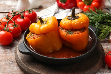 Photo of Tasty stuffed peppers in pan and products on wooden rustic table, closeup