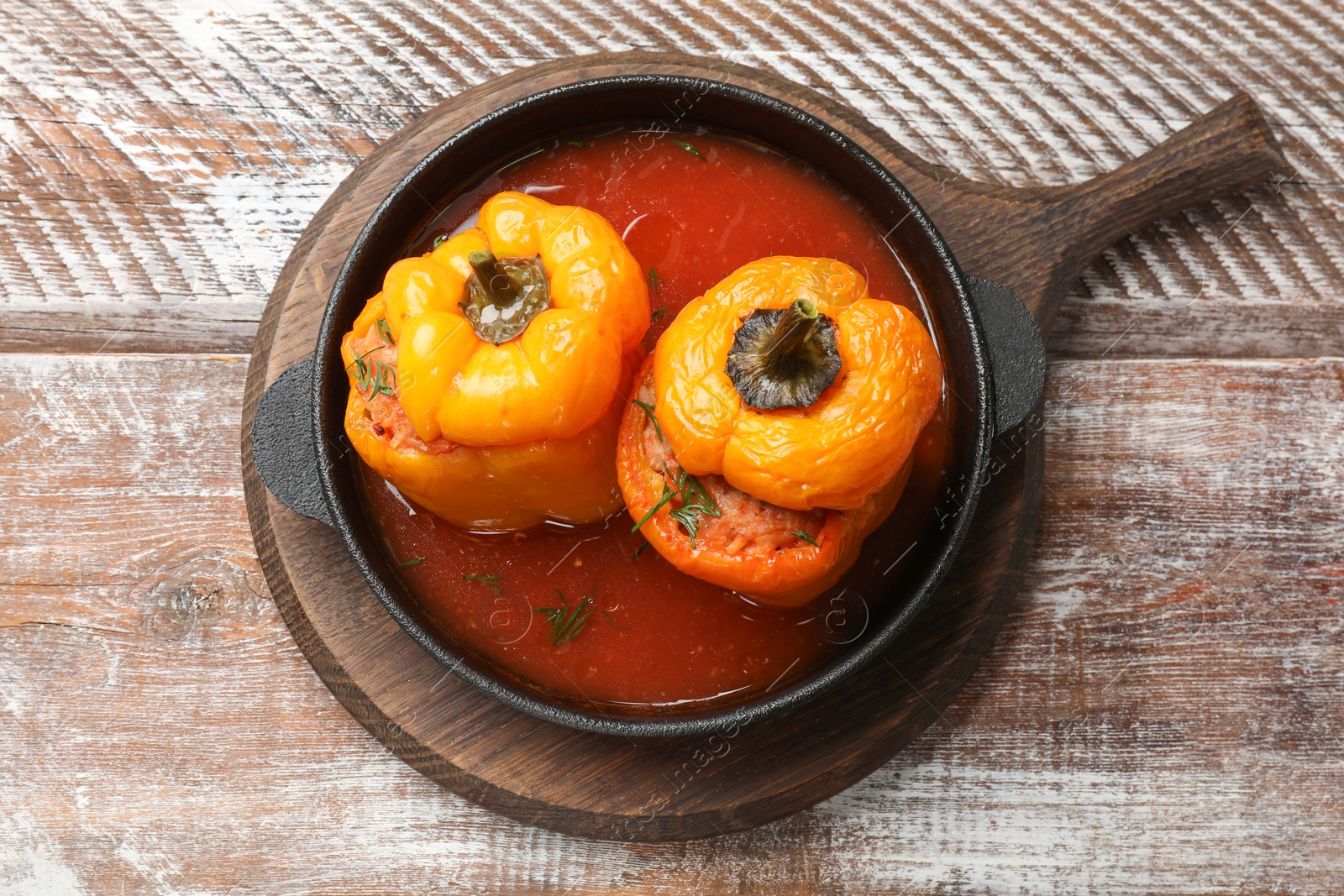 Photo of Tasty stuffed peppers in pan on wooden rustic table, top view