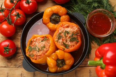 Photo of Tasty stuffed peppers, sauce and products on wooden table, flat lay