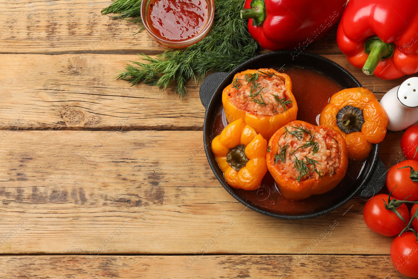 Photo of Tasty stuffed peppers, sauce and products on wooden table, flat lay. Space for text